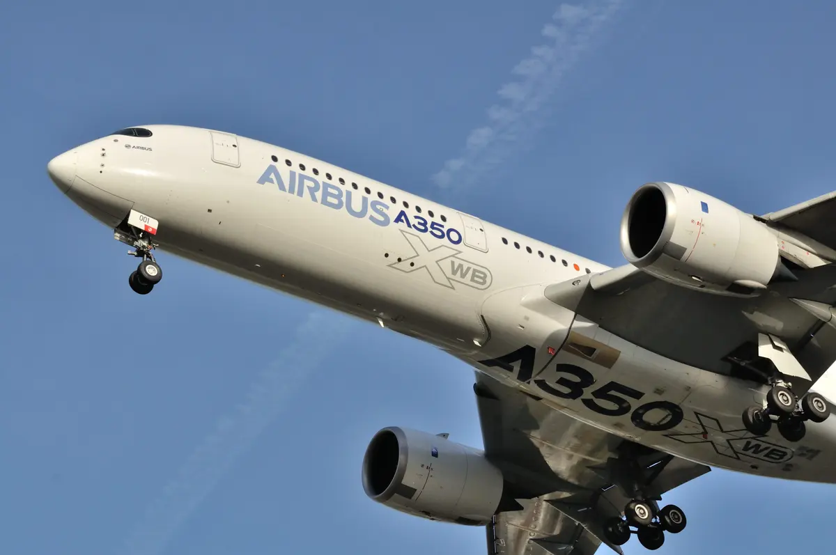 O nariz e o motor esquerdo de um Airbus A350 vistos de baixo na aproximação, com o trem de pouso estendido.